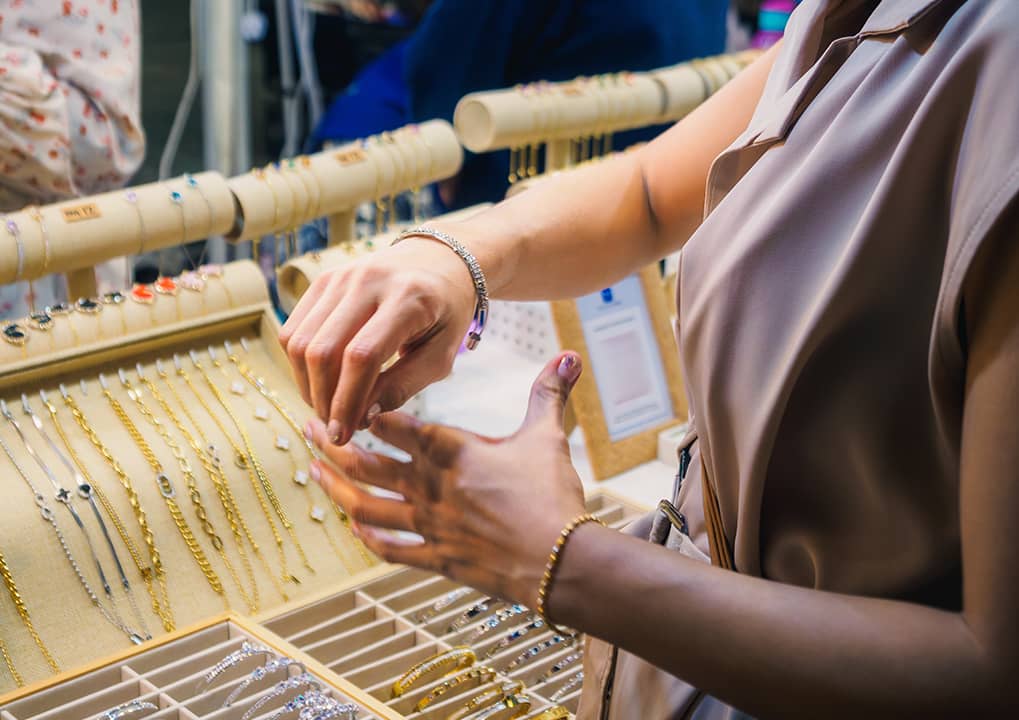 Close up of a woman trying on jewelry at a store.